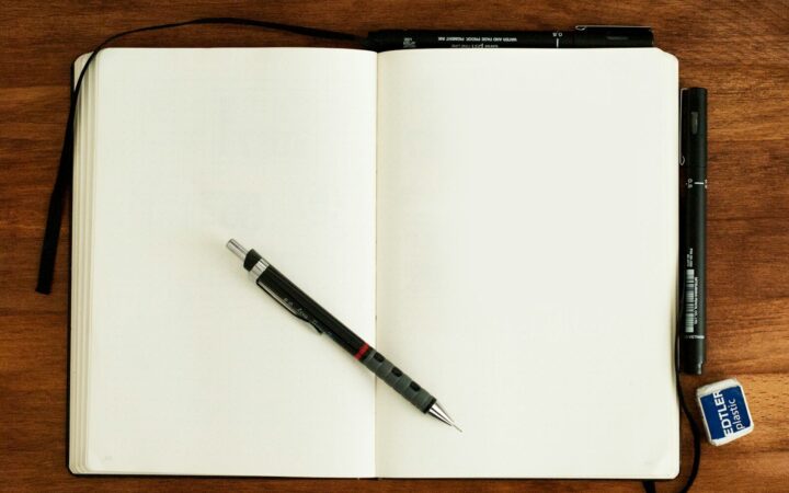 Cuaderno abierto con un bolígrafo sobre una mesa, listo para anotar ideas