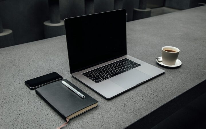 Portátil y taza de café sobre una mesa de trabajo vista desde arriba